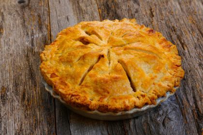 Delicious whole fresh baked rustic Apple Pie with table setting apple pie recipe